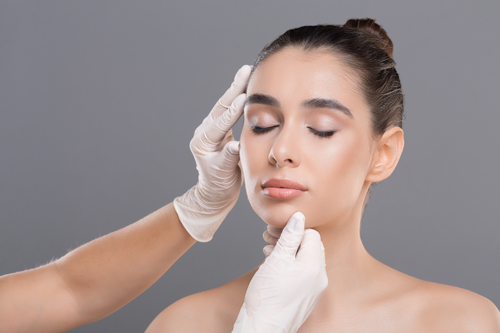 Young woman on consultation at beautician, grey background
