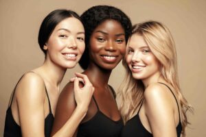 Beauty. Multi Ethnic Group of Womans with diffrent types of skin together and looking on camera. Diverse ethnicity women - Caucasian, African and Asian posing and smiling against beige background.