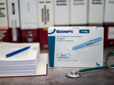 A Drug box of Ozempic containing Semaglutide for treatment of type 2 diabetes and long-term weight management on a table and in the background different medical books.